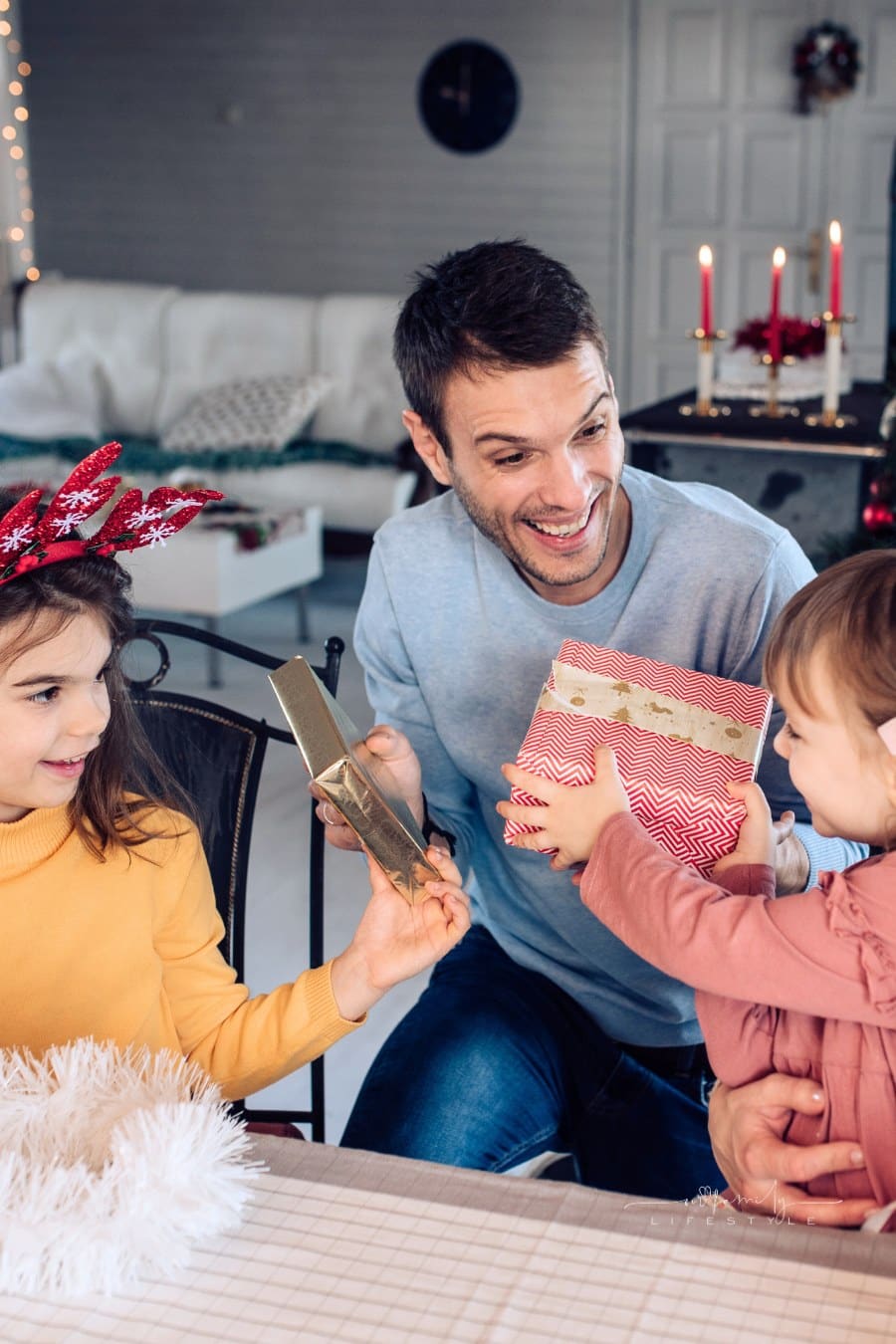 Two girls and their parents opening Christmas gifts together and having fun.