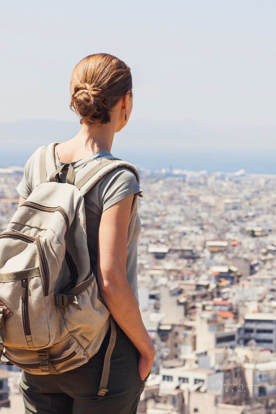 Young woman looking at a big city with backpack on