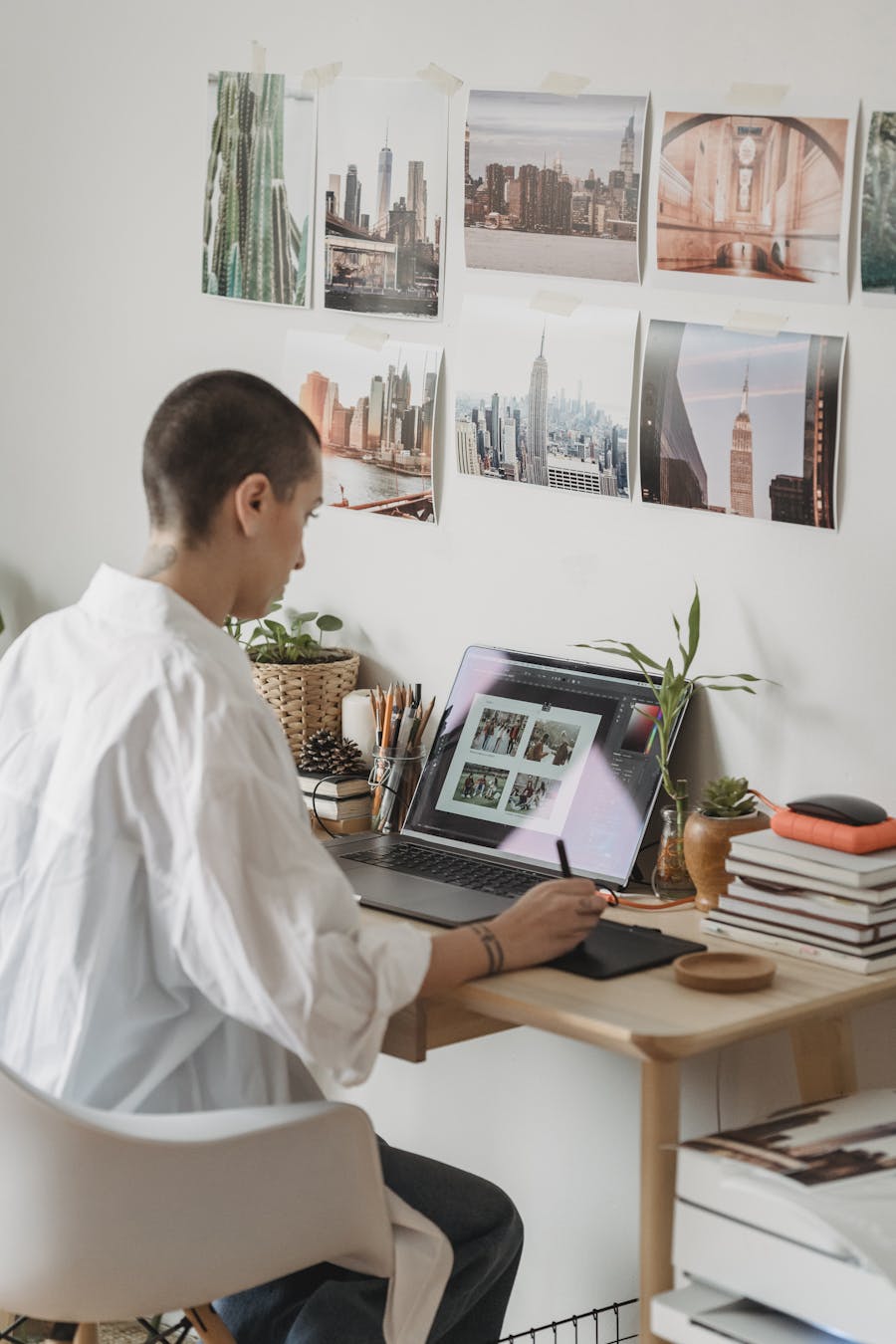 Woman editing photos on a laptop at a trendy indoor workspace with cityscape decor.