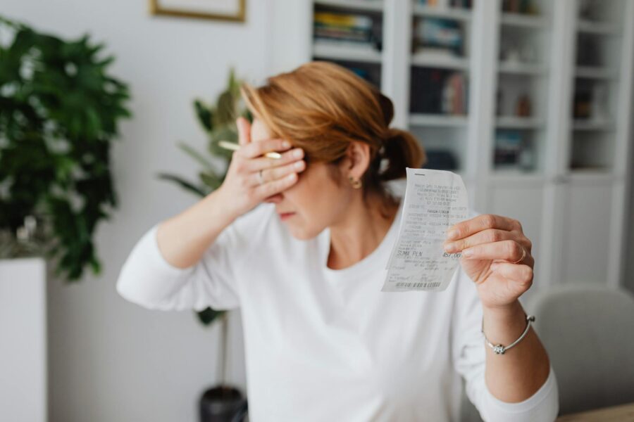 Woman experiencing stress while reviewing household expenses at home.