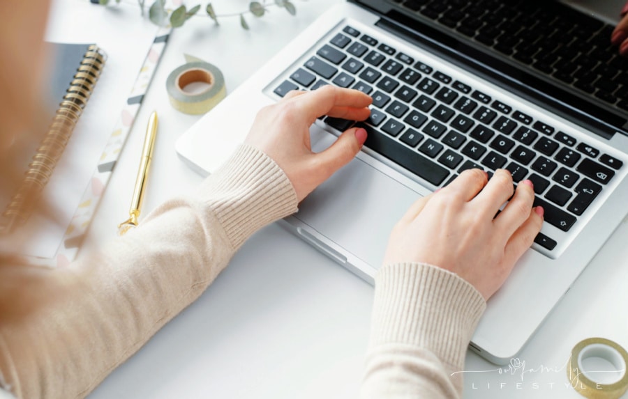 woman wearing cream sweater typing on laptop