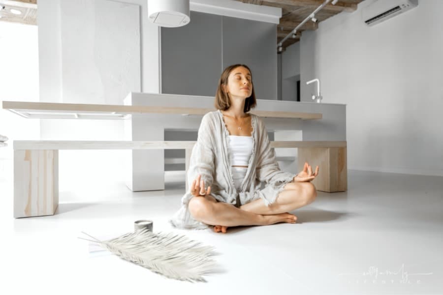 woman sitting in lotus position on floor in her home