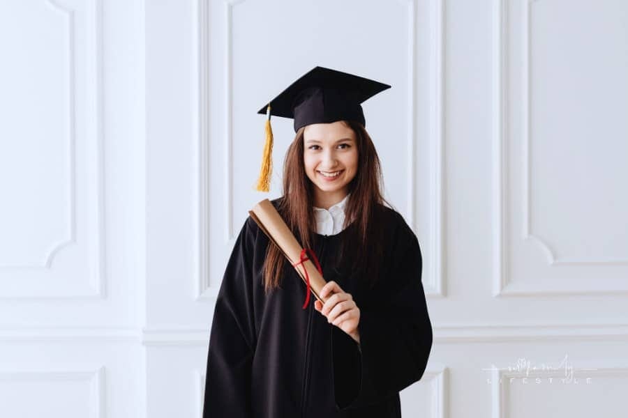female graduate in cap and gown holding a scroll diploma
