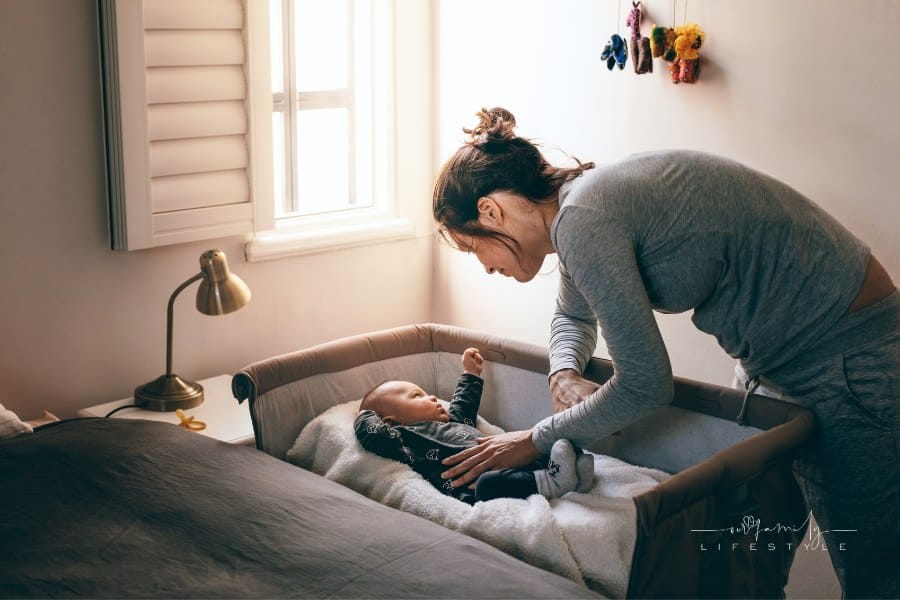 Young Mother Looking at Her Baby Sleeping in a Crib