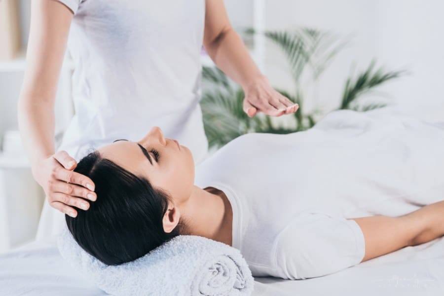 woman receiving Reiki healing treatment on head and chest