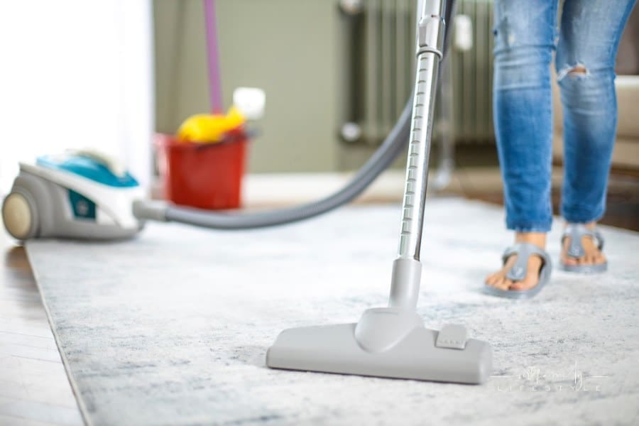 Young woman cleaning house with vacuum cleaner