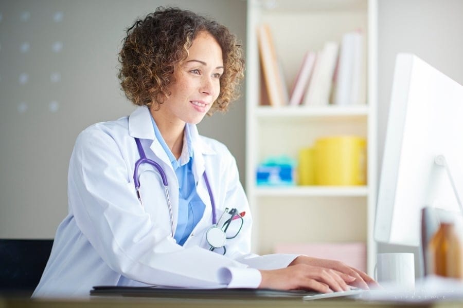 female doctor keying patient information into computer