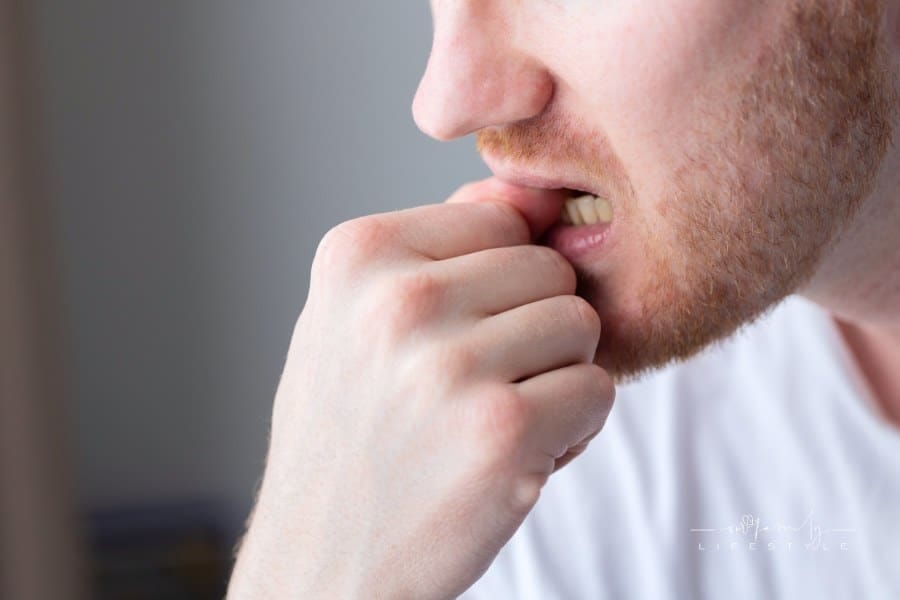 A man chewing on his fingernails with a worried expression. Closeup.