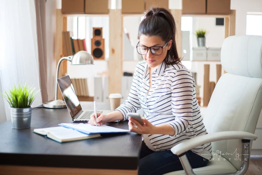 pregnant woman looking at phone while working at desk