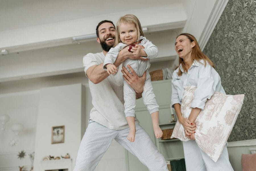Cheerful family with parents playing and lifting child in a cozy living room.