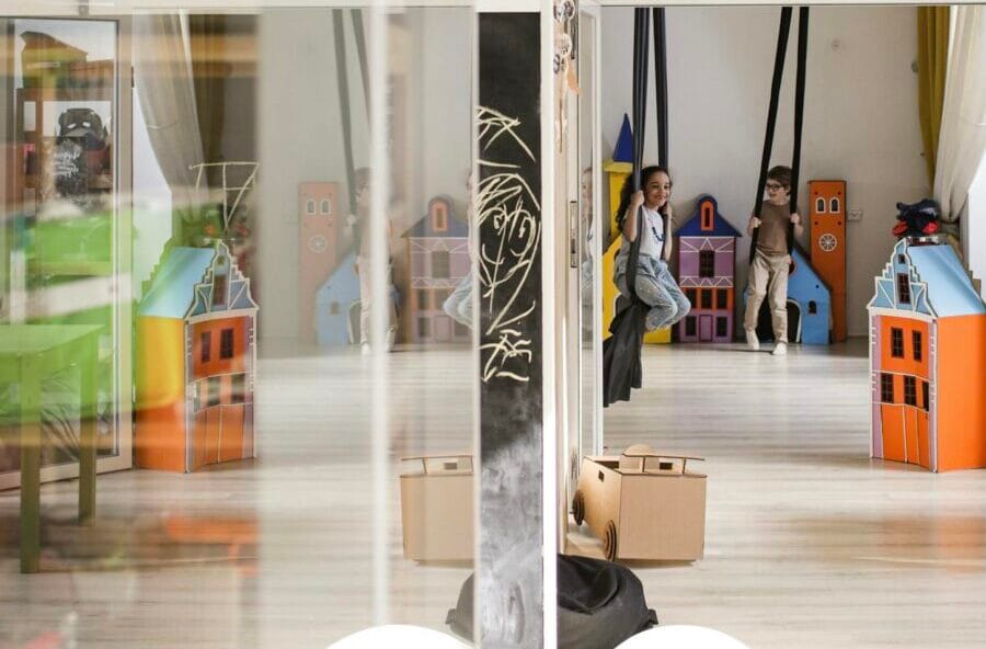 Children engaging in play with colorful toys in a bright, modern kindergarten classroom.