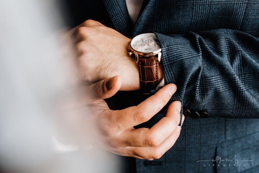 man checking luxury watch on wrist under sleeve of suit