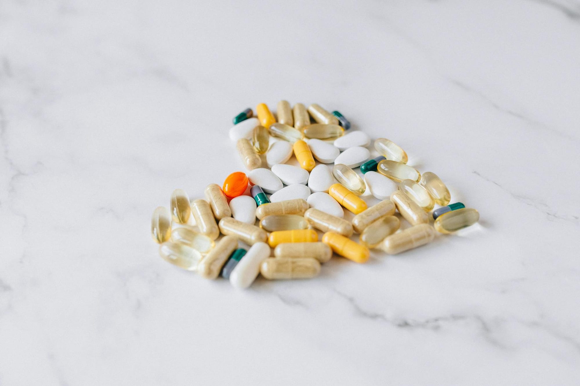 Close-up of various pills and supplements on a marble background, symbolizing health care and wellness.