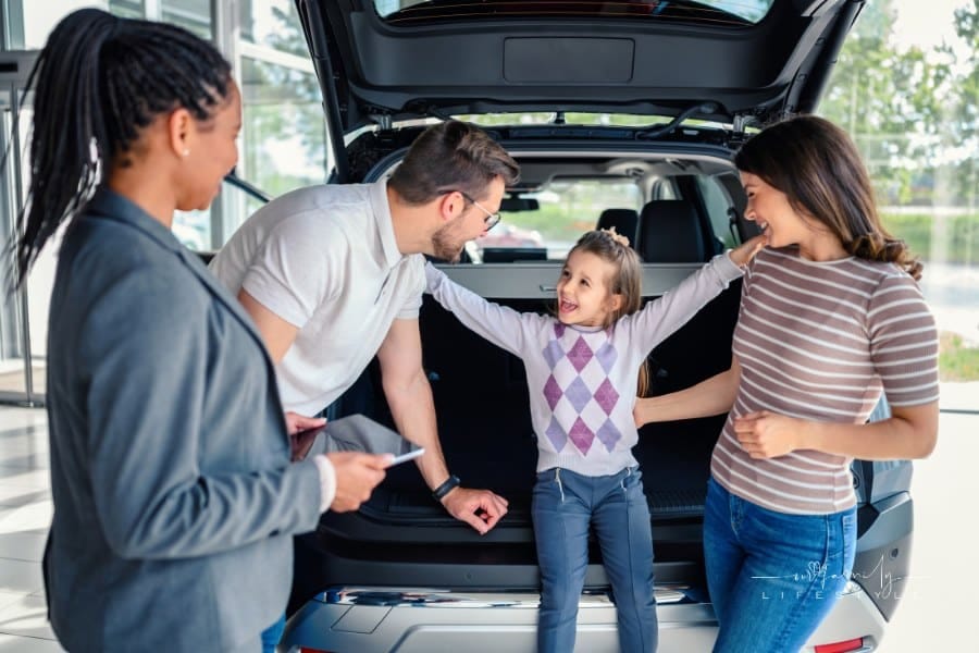 Saleswoman at car dealership center helping family to choose new family vehicle