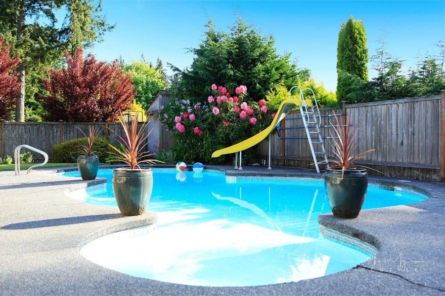 Fenced backyard with small beautiful swimming pool with slide