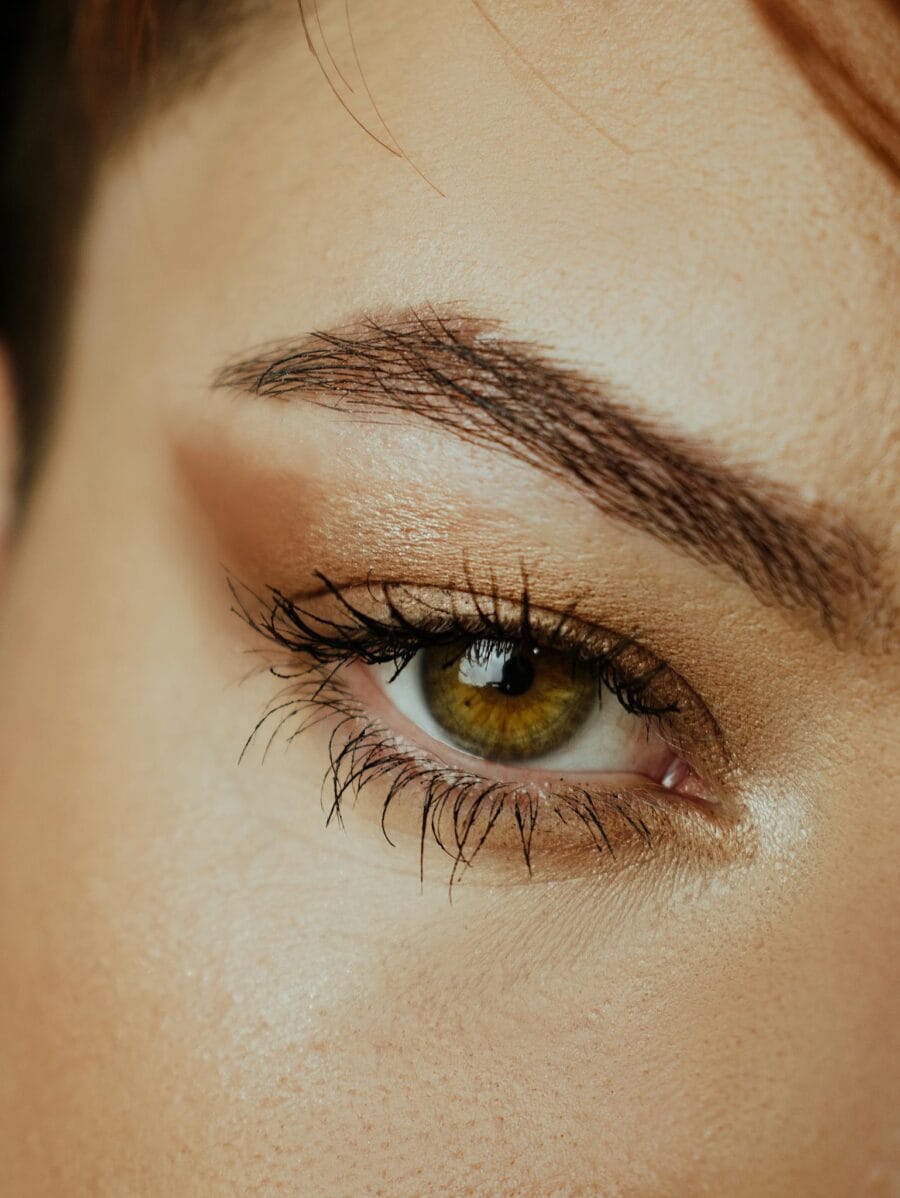 Detailed close-up of a woman's green eye with makeup, showcasing eyelashes and brow. What If You’ve Never Used a Brow Serum —