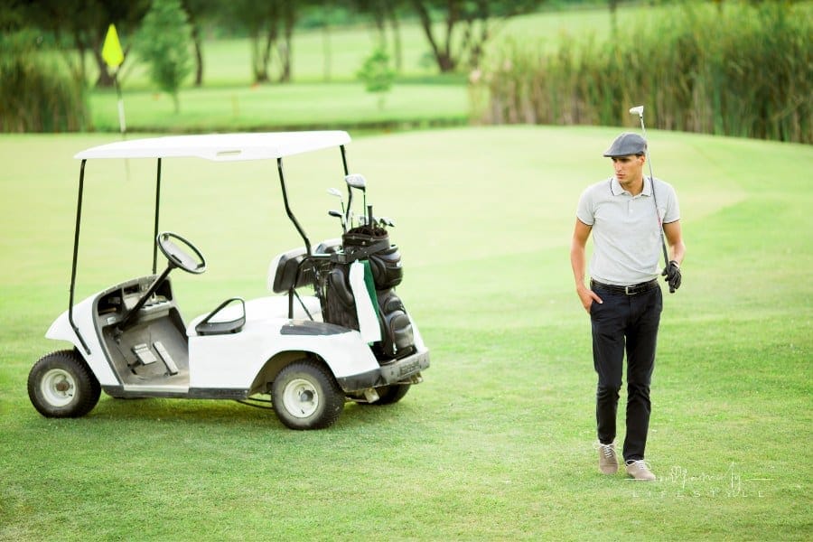 young golfer walking on golf course next to golf cart