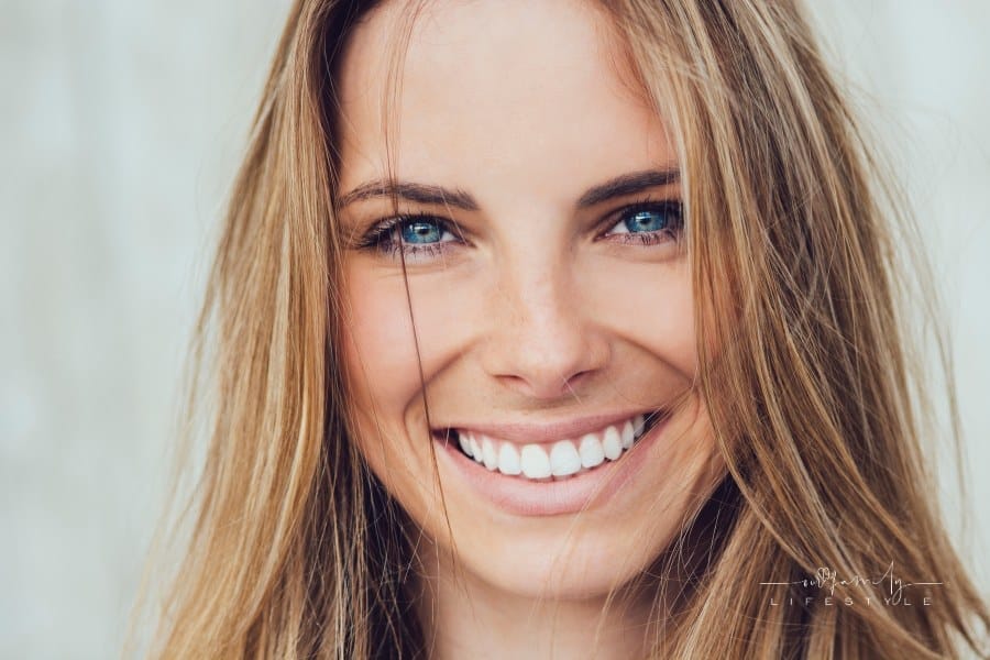 blond woman with blue eyes smiling with pearly white teeth