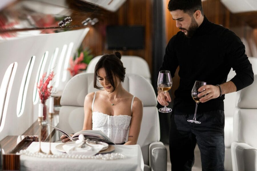Elegant couple enjoying wine in a luxurious private jet interior.