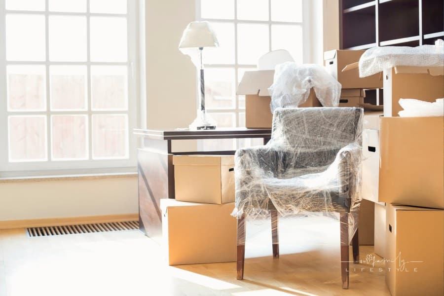 moving boxes surrounding an accent chair wrapped in plastic