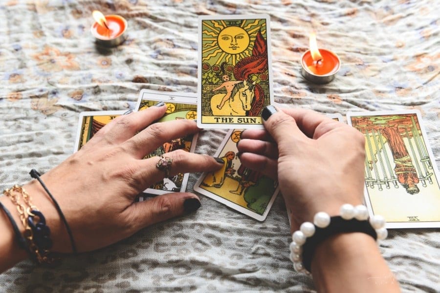 fortune teller's hands holding tarot cards over candellit table