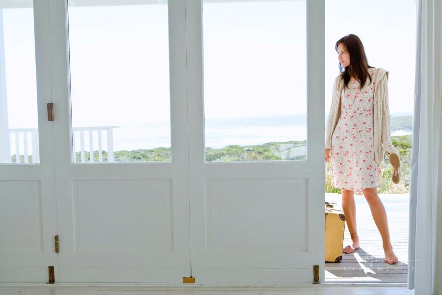 Woman arriving at beach house with suitcase