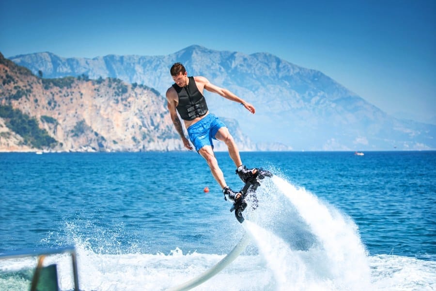 Closeup side view of a young man enjoying flyboarding session at sea on a sunny summer day.