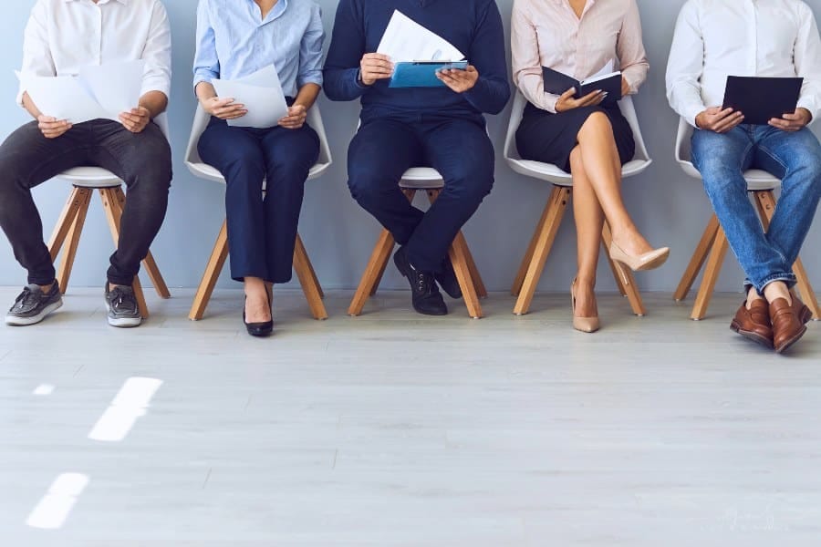 job seekers sitting in a row of chairs awaiting interview