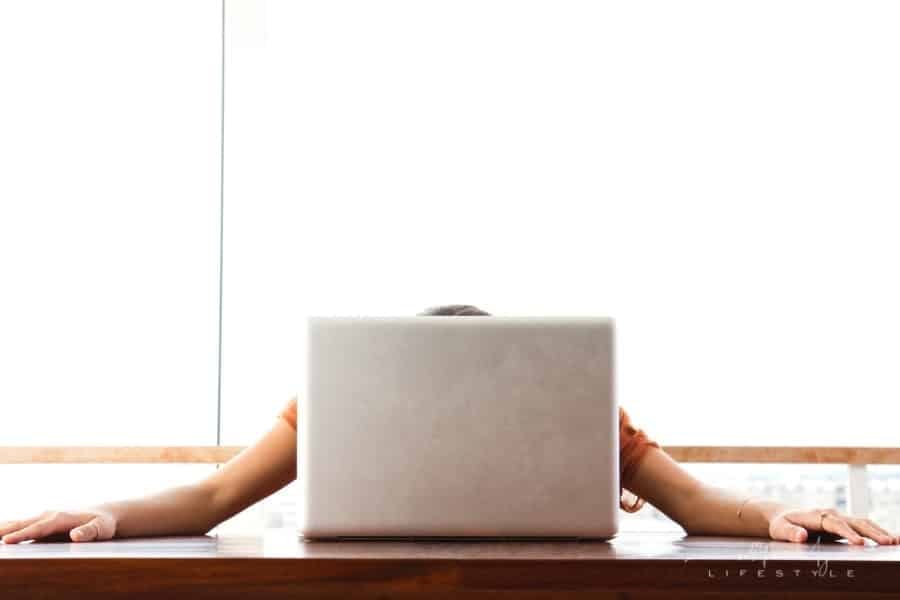 young frustrated woman with head rested on laptop and arms spread on desk