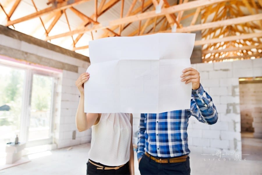 Young Couple looking at blueprints at Construction Site of new home