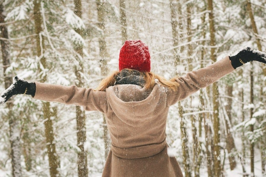 Woman Wearing Brown Coat with her amrs open standing in the snow