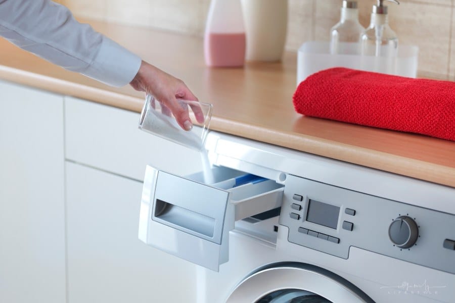 woman's hand pouring powder detergent into washing machine