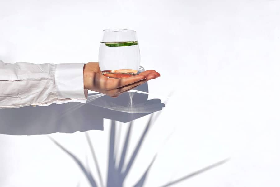 woman's hand holding out a glass of water