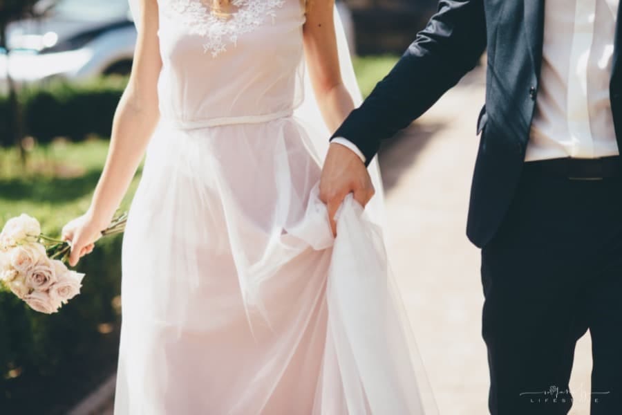 bride with rose bouquet walking with groom while holding hands