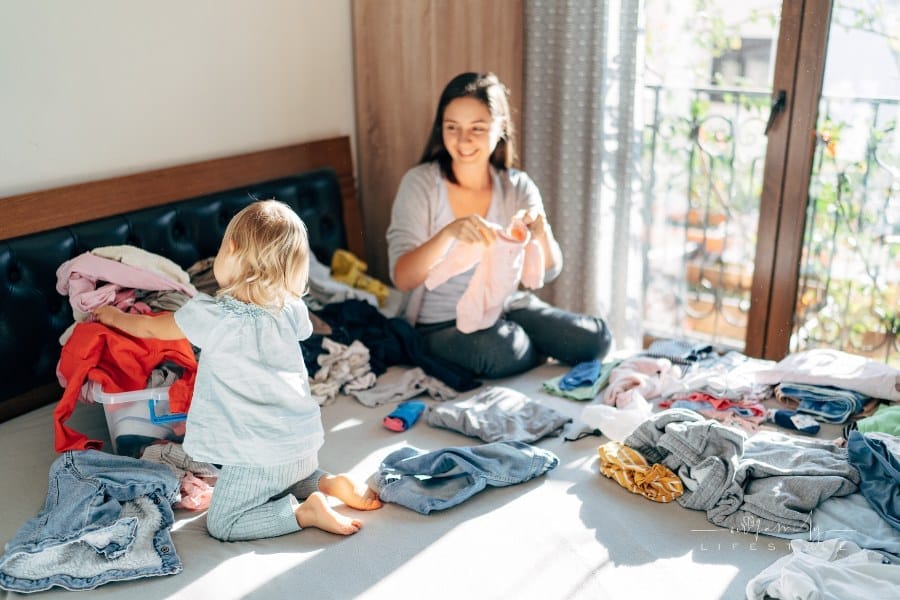 Mom and Daughter Folding Clothes on Bed