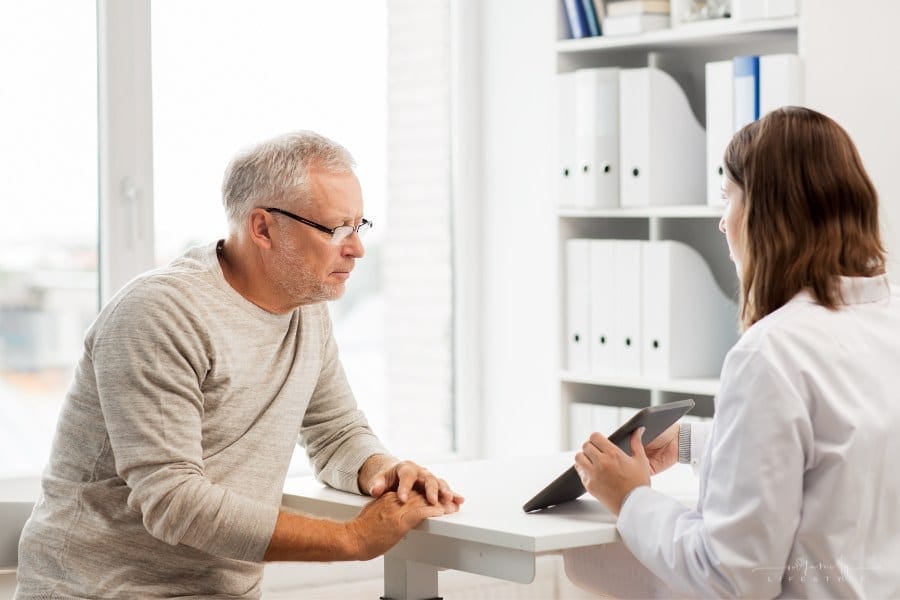 senior man looking at tablet being held by female doctor