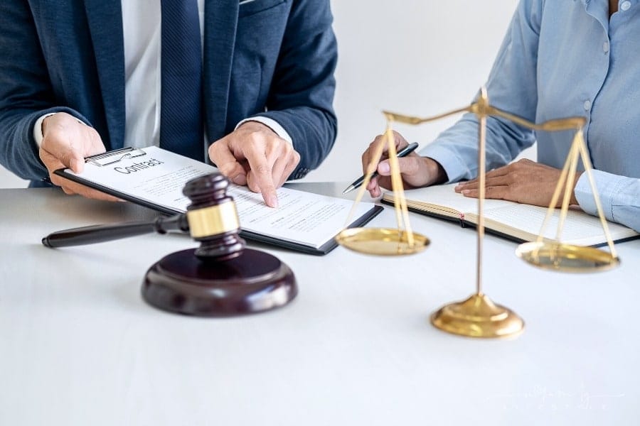 lawyer and client consulting behind legal scale and gavel