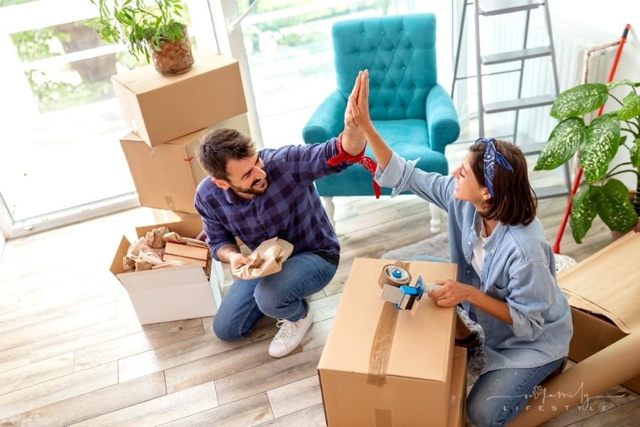 couple high-fiving over moving boxes in new house