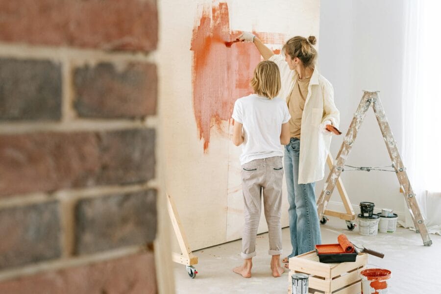 Mother and son collaborate on painting a wall during a home renovation project.
