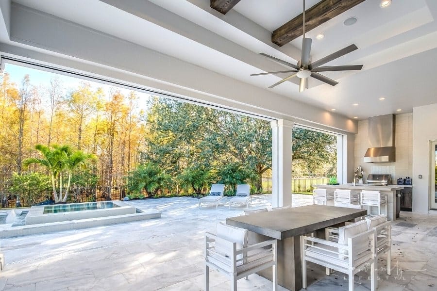 outdoor kitchen with dining table and chairs near swimming pool