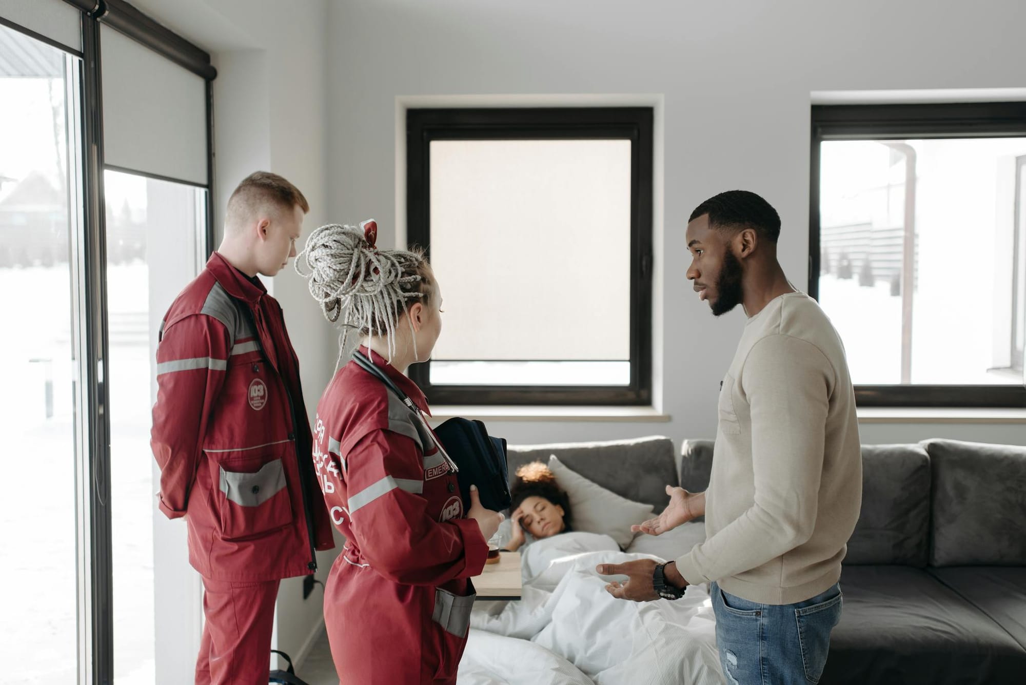 Paramedics assisting a patient at home, illustrating urgency and healthcare support indoors.