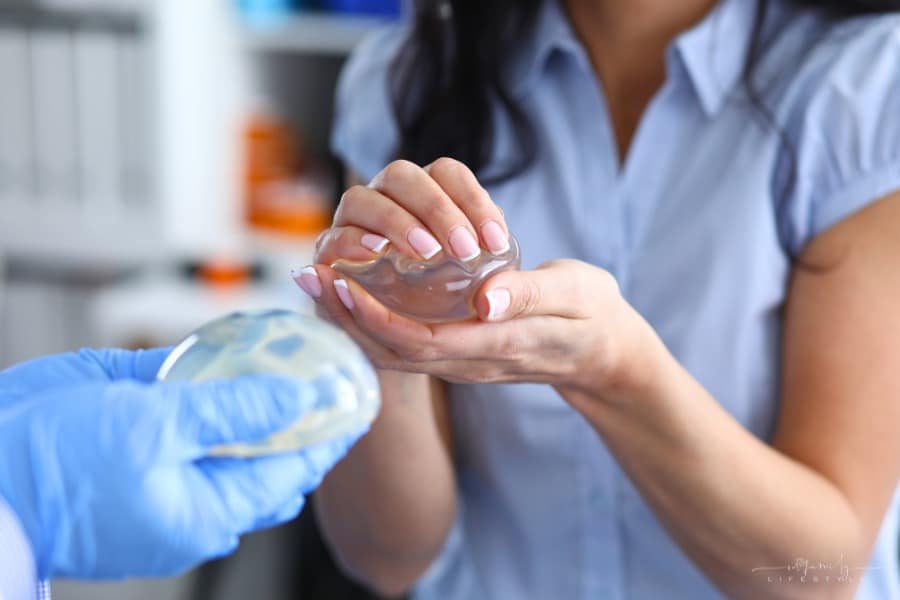 woman holding silicone implants while talking to doctor