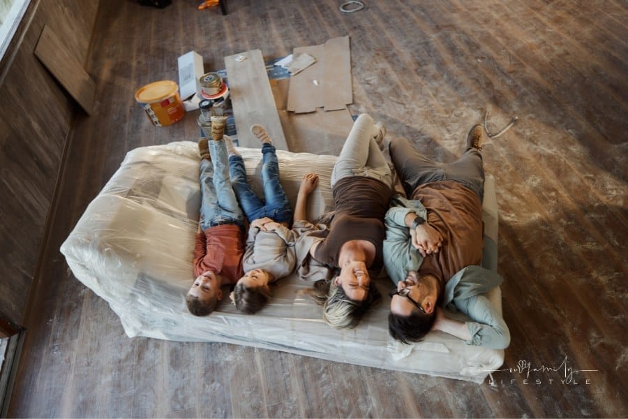 parents with small kids laying infloor with dust, paint, and tools around them during house renovation
