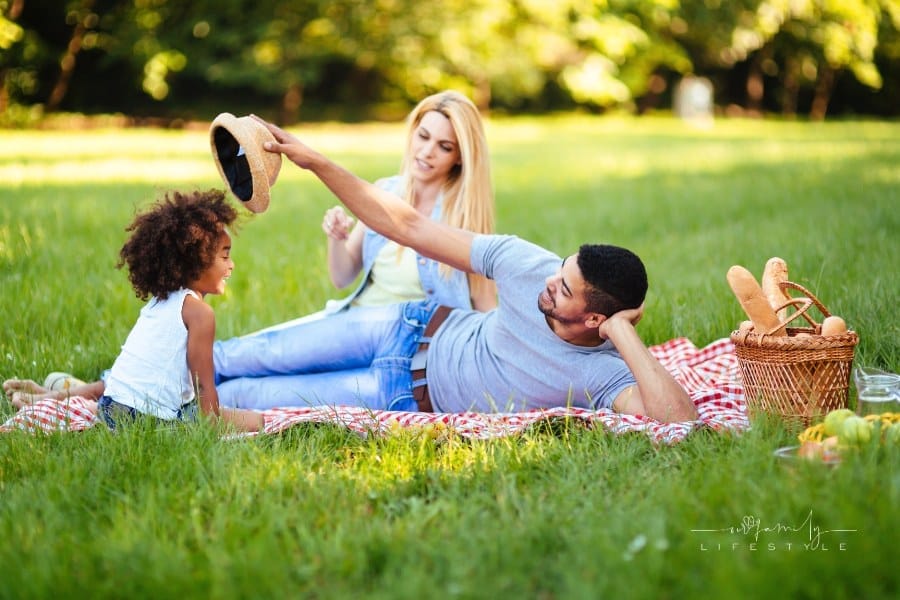 multiethnic couple having picnin outdoors with their daughter