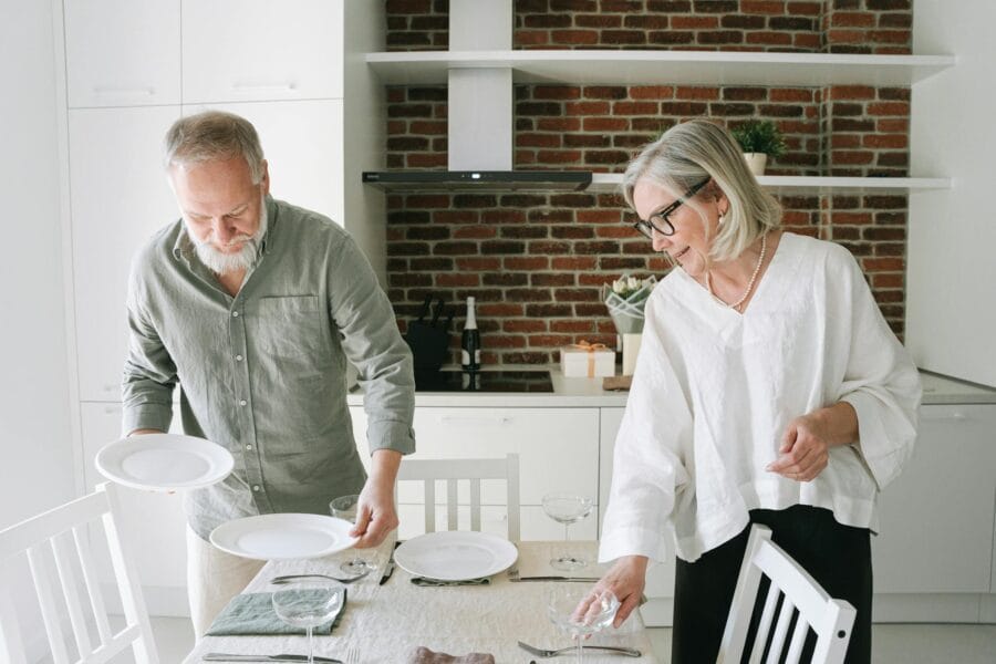 Senior couple enjoying quality time setting the table in their modern kitchen.