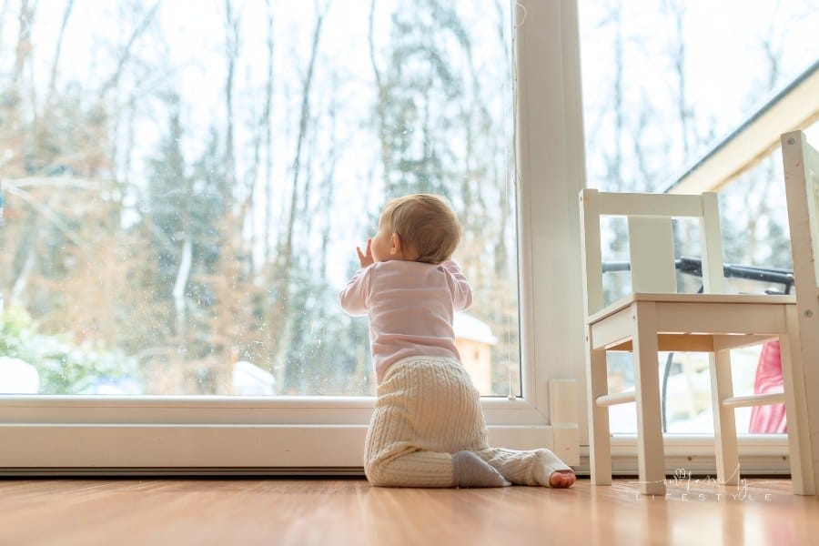 Baby Looking Outside Large Window During Winter