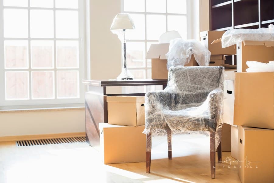 moving boxes and wrapped furniture in front of large windows