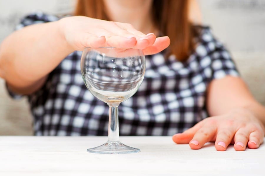 woman putting hand over wine glass to signal no more