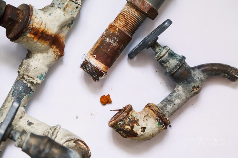 Dismantling of old pipes. Pieces of old rusty metal pipes and taps lie on a white background. Close-up