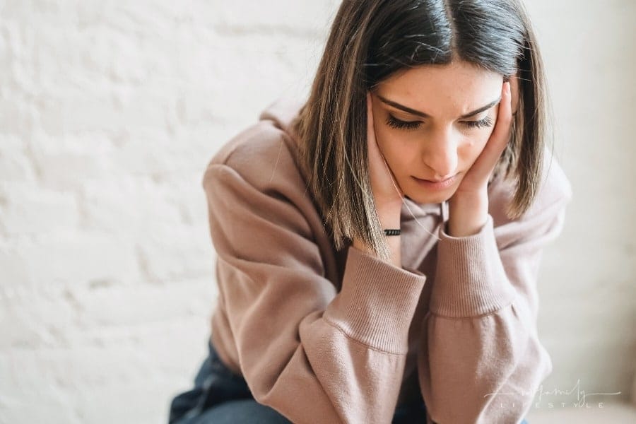 young woman holding head in hands with stress
